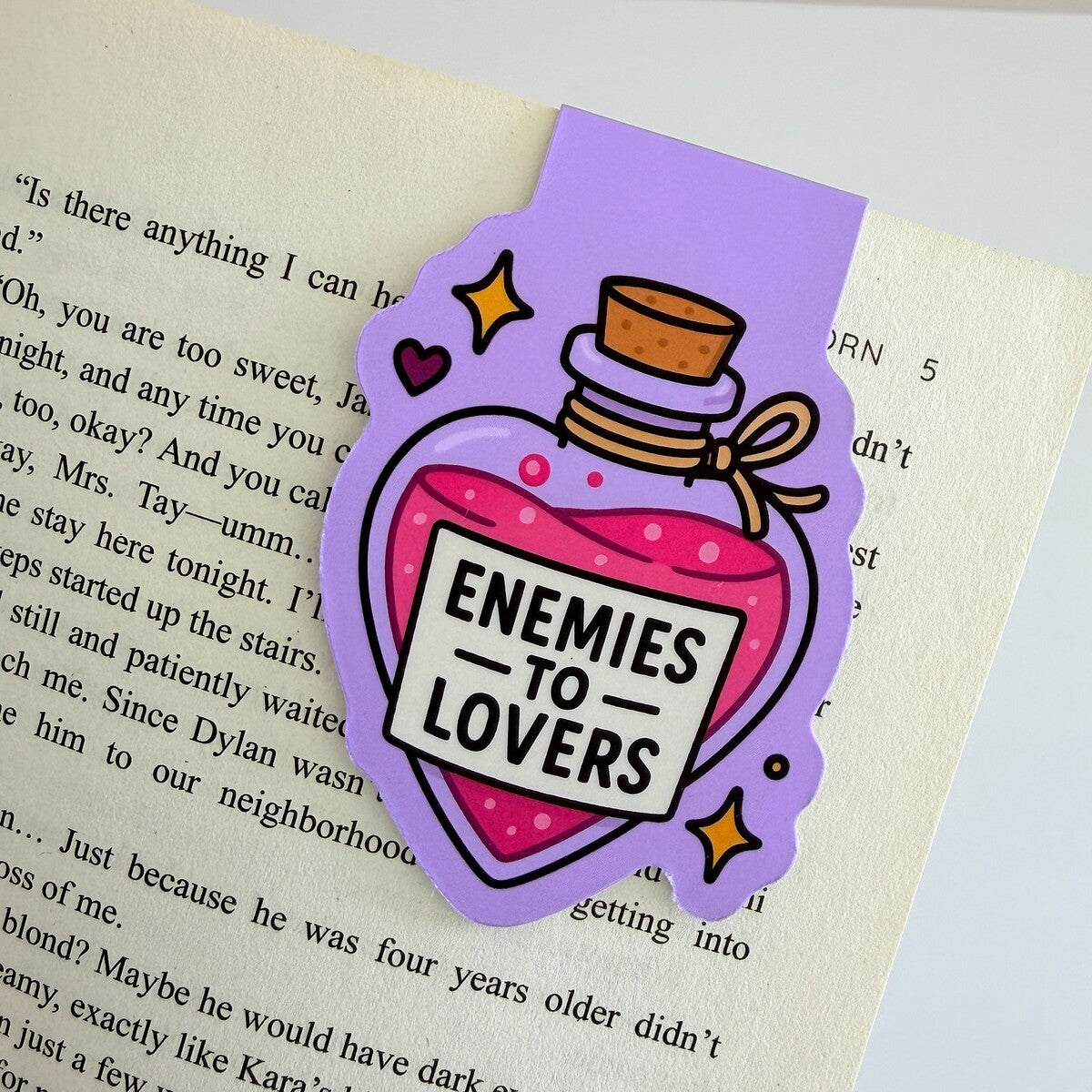 Enemies to Lovers magnetic bookmark clipped to an open book page